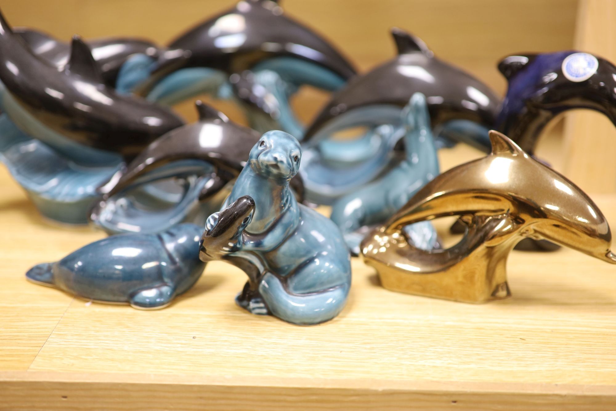 Six Poole pottery dolphins together with two similar seals and an otter